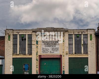 Derelict Banana Warehouse building in York, formerly home to a used furniture store, with cracked paint, broken windows and faded signage on a cloudy Stock Photo