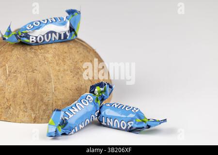 Three Bounty, small chocolate bars on half a coconut on a white background Stock Photo