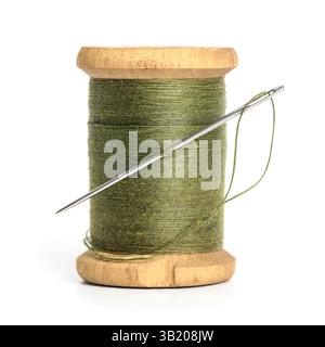 Old Single wooden spool of thread olive green color and needle Simple design of thread closeup white background Stock Photo
