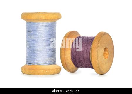 Old retro sewing blue purple colored thread spools isolated on white background Stock Photo