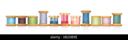 A row of old retro sewing colored thread spools reflections isolated on white Stock Photo