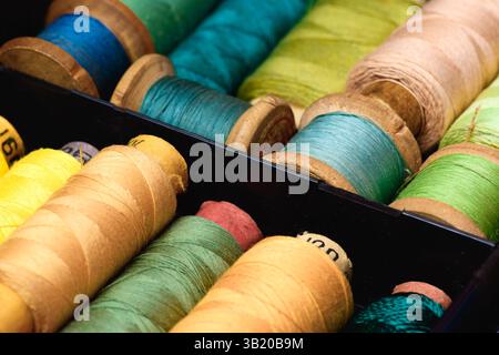 Lot of Colored spools with thread in dark plastic box close up background Stock Photo
