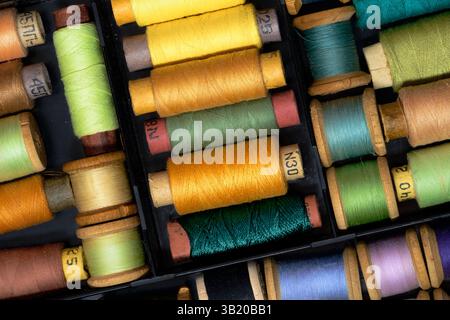 Lot of Colored spools with thread in dark plastic box close up background Stock Photo
