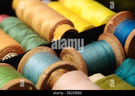 Lot of colored spools different sizes with thread in box closeup Stock Photo