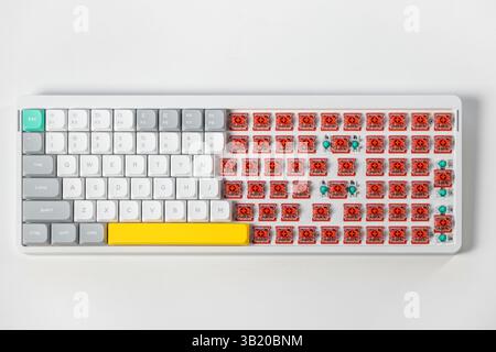 Top down view of a mechanical keyboard with some keycaps removed showing red low-profile switches illustrating computer hardware assembly or maintenan Stock Photo