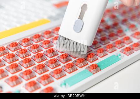 Soft-bristle vacuum cleaner removes dust from red mechanical switches on a vibrant keyboard, capturing the detail of PC customization, cleanliness, an Stock Photo