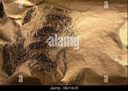 Bronze and brass foil background with crumpled texture and shimmer. Metallic surface with sparkle, glow, and gradient creates a polished, festive, com Stock Photo