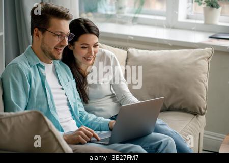 Happy Couple Using Laptop at Home Stock Photo