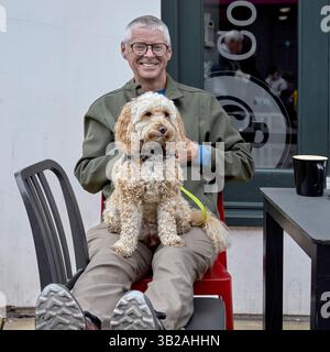 Cockapoo dog and owner relaxing at pavement coffee shop, Stratford upon Avon, England, UK Stock Photo