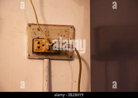 Old Electric Outlet with Plugged Cords on a Wall Indoors Stock Photo
