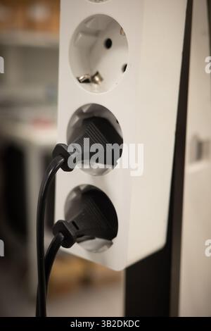 Power strip with multiple plugs connected in office environment. Stock Photo