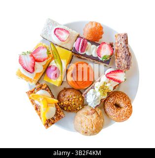 various sweet cakes with fruits and coconut chips on plate, top view, isolated on white background with clipping path Stock Photo