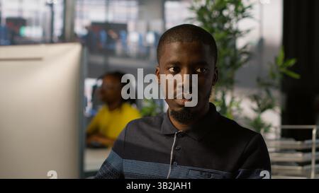 Upbeat software engineer utilizing cloud computing resources to train and deploy large scale machine learning models. Jolly man monitoring company systems, ensuring their reliability, camera A Stock Photo