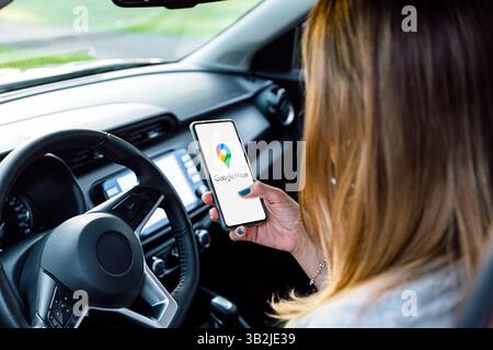 Woman in a car looking her phone with Google Maps in the screen. ROSARIO, ARGENTINA - APRIL 22, 2025. Stock Photo