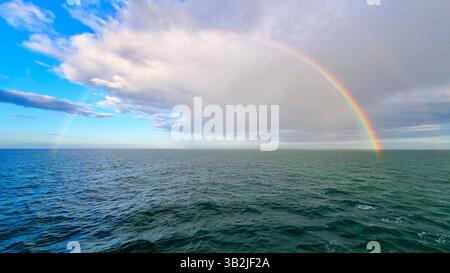 Double Rainbow over the waters of the Atlantic Ocean against a background of white clouds and blue sky after spring rain Stock Photo