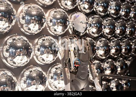 Robot working at computer among people. Maschine typing on keyboard in office. IT team of future. Futuristic worker. Humanoid work at call center. Sup Stock Photo