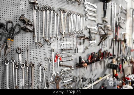Various wrenches and hand tools systematically arranged on pegboard in workshop providing organized storage solution for mechanical repairs and maintenance Stock Photo