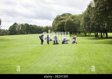 Person, golf cart and mobility aid with group on field for paragolfer or adaptive sports, teamwork or walking. People, support and lawn for Stock Photo