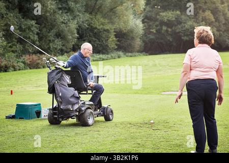 Sports, person with disability and trainer for golf game, match and competition on golfing course. Recreation, mobility scooter and woman and man with Stock Photo
