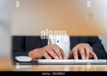 Using computer, hand typing message on keyboard laptop chatting friend and search information form internet. Closeup of Indian businessman typing on k Stock Photo