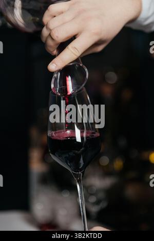 Red wine pouring into the glass with hand on a white background Stock ...