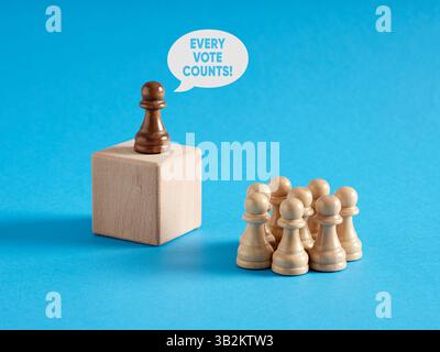 Leader chess pawn at the rostrum gives the message of Every Vote Counts to the crowd of audience. Political activism, voting and democracy. Stock Photo