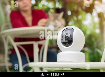Family and pet protection concept. Security camera high tech smart gadget standing in the garden with pet and owner. Stock Photo