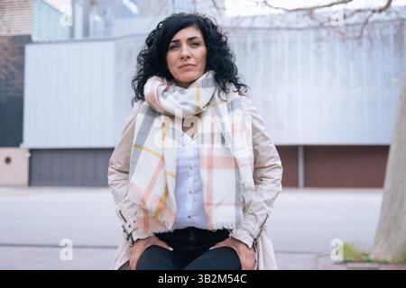 individual portrait Confident woman with curly black hair and scarf smiling  Stock Photo