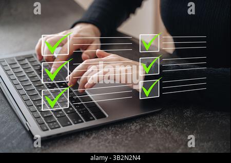 A digital to-do list overlay appears above a person working on a laptop, emphasizing productivity Stock Photo