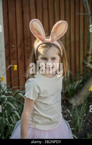 Bunny toddler girl searching for chocolate eggs in garden Stock Photo