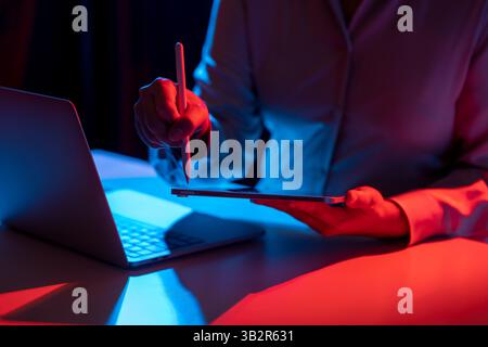 Businesswoman using a tablet with a pen while working at a table. Laptop computer beside the tablet. Mockup and copy space. Business and technology co Stock Photo