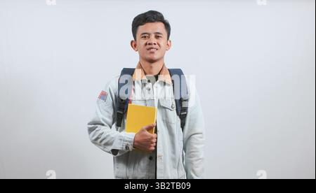 asian man wearing denim jacket carrying bag and books isolated on white background Stock Photo