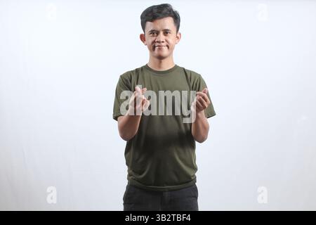 Asian man wearing green t-shirt smiling giving love sign isolated on white background Stock Photo