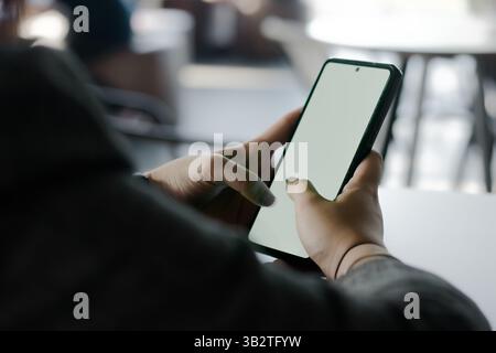 A person interacts with a smartphone. The hands hold the device with a blank, bright display, suggesting possibilities for digital engagement and app Stock Photo