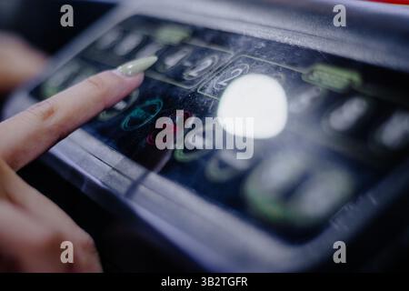 A woman's finger pressing on a treadmill console, ready to start a workout. The control panel is slightly dusty. The machine is ready to use for a hea Stock Photo
