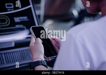 A person interacts with a digital display screen using mobile technology, suggesting modern connectivity, interactive interfaces, and digital innovati Stock Photo