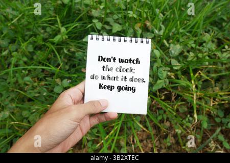 Notebook with motivational quote 'Don't watch the clock; do what it does. Keep going' about perseverance and consistency concept Stock Photo