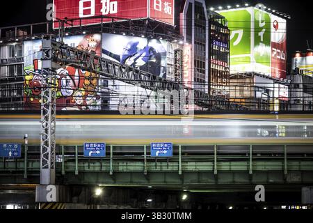 TOKYO, JAPAN, SEPTEMBER 16 2024: Train and traffic in Tokyo's busy Shinjuku neighborhood at night in Japan Stock Photo