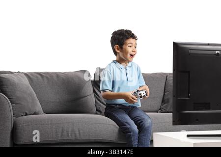 Excited asian kid sitting on a sofa and playing video games isolated on white background Stock Photo