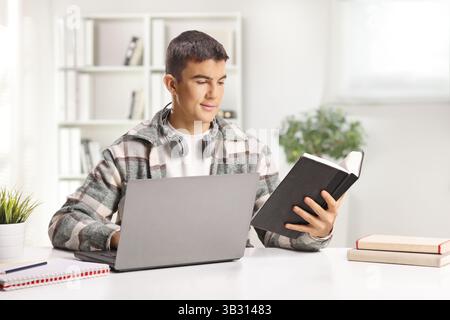 Male student studying with a laptop computer and a book at home Stock Photo