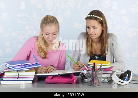 Two teengirls sitting at desk making homework together Stock Photo
