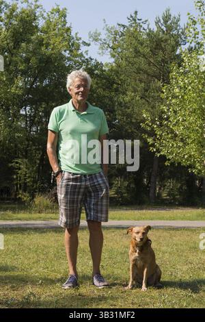 Senior man standing with dog in summer Stock Photo