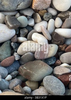 Macro photo of colorful smooth pebbles on the beach with natural textures and rounded shapes in soft daylight Stock Photo
