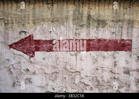 Red arrow pointing left, painted on an old abandoned wall Stock Photo