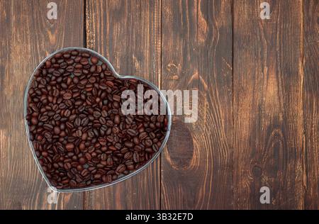 Heart full of coffee beans. Coffee lovers concept. Start of the day. Top view, wooden dark background. Stock Photo