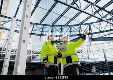 Construction managers using digital tablet on site, reviewing project plans. Stock Photo