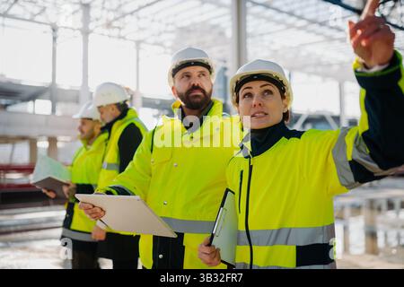 Team of engineers and construction workers inspecting building progress. Stock Photo