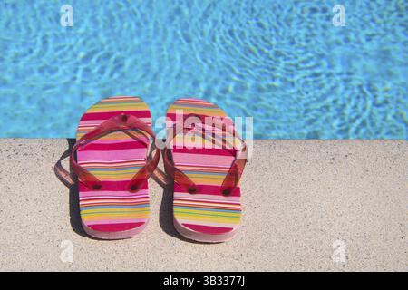 Colorful striped flip flops at the swimming pool Stock Photo