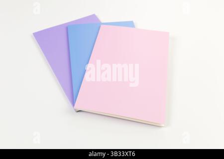 Top view of pink, purple and blue notebooks on white background. School, office wallpaper. Flat lay, copy space. Stock Photo