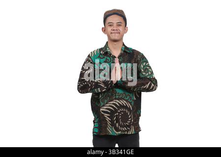 Asian man wearing batik shirt and Javanese blangkon smiling expression giving greeting Stock Photo